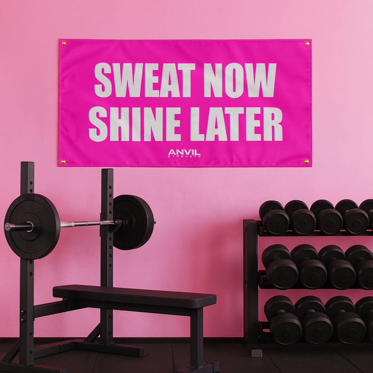 Motivational gym flag with inspirational text saying, "Sweat now shine later". Pink flag with white text in a home gym.