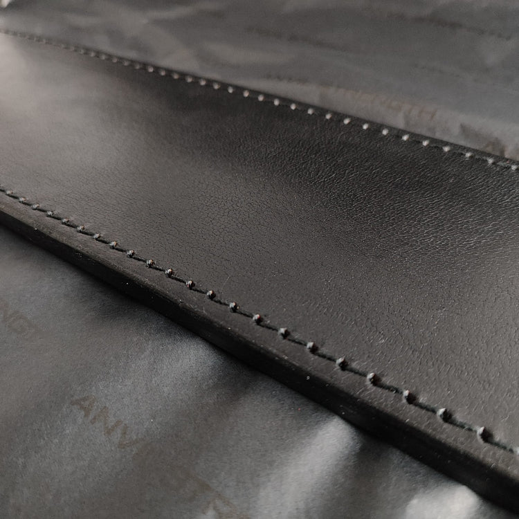 Close-up of a black leather belt with stitching detail, featuring the brand name 'Anvil Strength' on a black background.